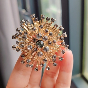Macro shot of vintage gold sunburst flower brooch with grey rhinestones detail