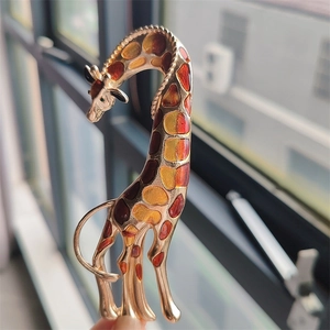 Close-up of giraffe brooch with colorful enamel spots and a green gemstone eye
