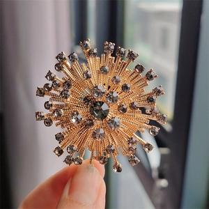 Macro shot of a vintage sunburst flower brooch with grey crystals and a gold alloy finish