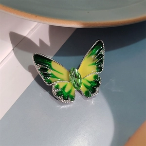 Detailopname van vlinderbroche met groene emaille vleugels en kristallen inleg