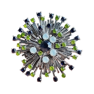Vintage silver sunburst brooch with blue and green crystals on white background
