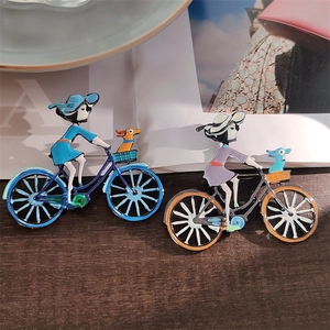 Vue détaillée d'une broche en émail coloré fille à vélo sur un fond de bureau en bois