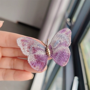 Macro shot of delicate purple and blue embroidered butterfly wings with golden metal body