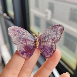 Macro detail of the purple gradient embroidered butterfly brooch with gold metal accents
