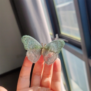 Detailed embroidery butterfly brooch with pastel gradient wings held by hand