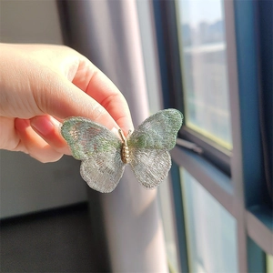 Detailed embroidery of a semi-transparent butterfly brooch with delicate silver lace wings