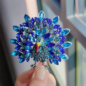 Detailed close-up of a vintage peacock brooch featuring blue marquise crystals and enamel