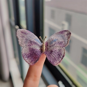 Handheld view of vintage purple embroidered butterfly brooch with gold metal body details
