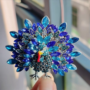 Close-up of a vintage peacock brooch with vibrant blue rhinestones on silver metal