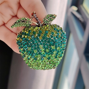 Detailed view of apple brooch featuring green gradient crystals and alloy stem