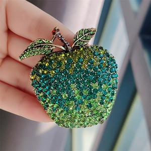 Detailed close-up of a vintage apple brooch encrusted with gradient green and red crystals