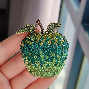 Macro detail of apple brooch with green and yellow rhinestones on a golden base