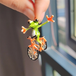 Detailed close-up of a creative frog riding bicycle brooch with vibrant enamel finish