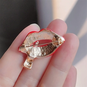 Detailed back view of a red enamel lip brooch featuring gold-tone plating and pin closure