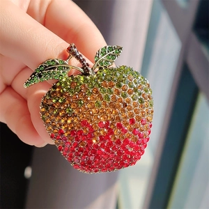 Close-up of a vintage apple brooch with colorful crystals and gradient red finish