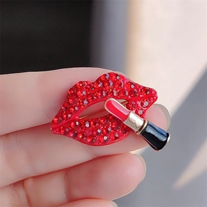 Macro view of crystal encrusted red lips and enamel lipstick brooch held by hand