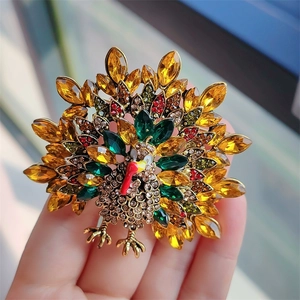 Close-up of a vintage turkey brooch with colorful rhinestones and amber gems in hand