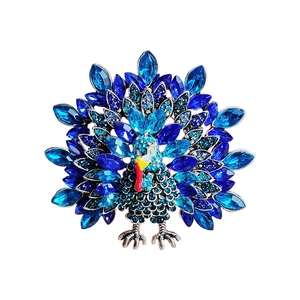 Exquisite peacock brooch with blue rhinestones and silver metal base on white background