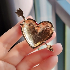 Detailed macro view of heart and arrow brooch back showing the pin closure and metal texture