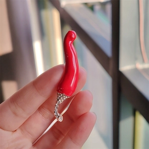 Détail macro de la broche piment en émail rouge avec strass dorés scintillants