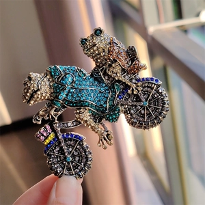 Detail of vintage frogs riding a motorcycle brooch with colorful rhinestones on silver alloy