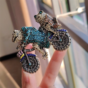 Detail of vintage frog prince riding motorcycle brooch with sparkling colorful rhinestones