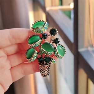 Macro view of vintage plant-shaped brooch featuring green cat-eye gems and rhinestones