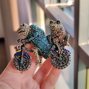 Macro detail of retro frog prince cycling brooch with sparkling colorful rhinestones