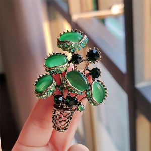 Close-up of vintage flower pot brooch with green opal stones and emerald crystals