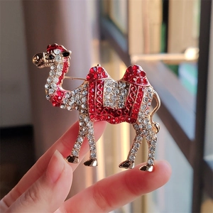 Detailed macro view of exotic camel brooch with vibrant red and white crystals in gold finish