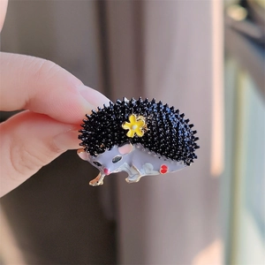Détail macro de la broche hérisson émaillée avec marguerite jaune et texture perlée
