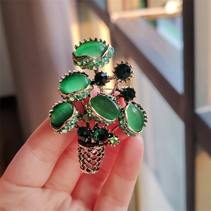 Luxurious gold flower pot brooch featuring green opal stones and sparkling green rhinestones
