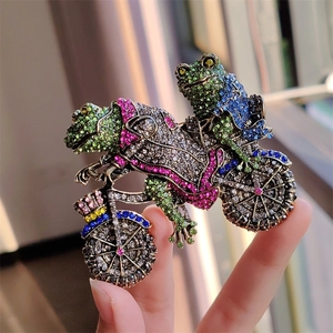 Macro detail of vintage frog riding motorcycle brooch with colorful crystal rhinestones