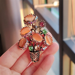 Detail of floral bouquet brooch with orange cat-eye stones and vibrant rhinestones