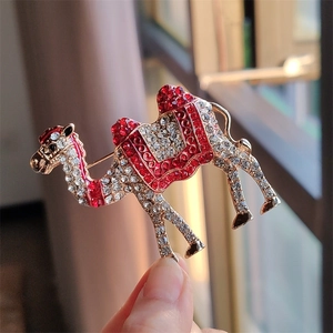 Detailed close-up of a vintage camel brooch featuring red enamel and sparkling rhinestones