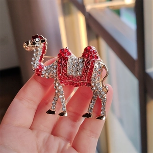 Close-up of a golden camel brooch with intricate red and white crystal inlay