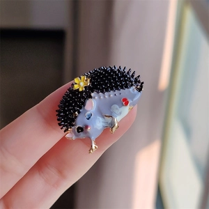 Gros plan d'une jolie broche hérisson en émail avec corps violet et fleur jaune