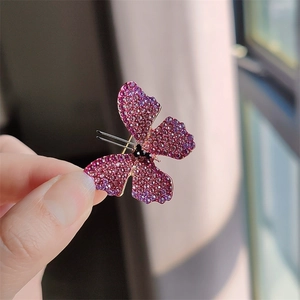 Close-up of butterfly brooch with purple gradient crystals and gold base being held