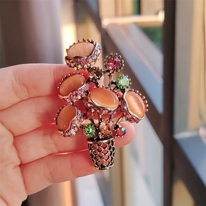 Detail of flower basket brooch with opal stones and colorful rhinestones held in hand