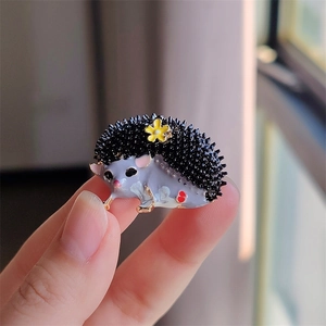 Détail de la broche hérisson avec finition émail violet et accent de marguerite jaune