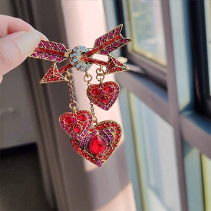Détail de la broche flèche de Cupidon vintage avec strass et pendentifs en cœur