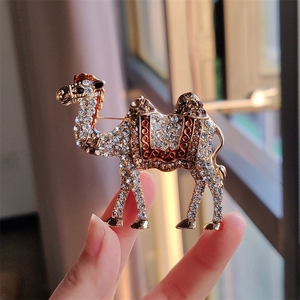 Detailed close-up of a vintage camel brooch with sparkling rhinestones and red enamel