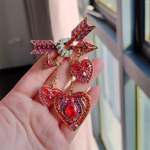 Gros plan détaillé d'une broche flèche de Cupidon vintage avec glands en cœurs de cristal