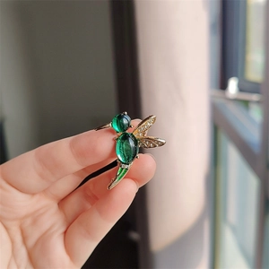 Close-up of hummingbird brooch with green opal stones and sparkling rhinestone wings