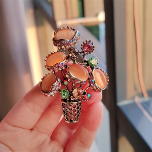 Detail of flower basket brooch featuring orange cat eye stones and colorful rhinestones