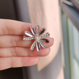 Dettaglio di una spilla a margherita in cristallo viola con strass bianchi brillanti