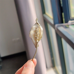 Macro detail of calla lily brooch with white enamel petals and crystal encrusted stamen