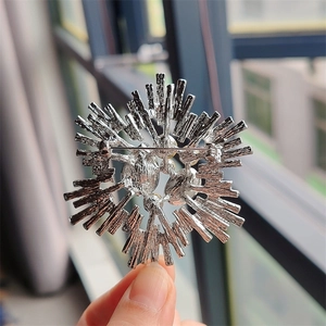 Macro shot of silver crystal brooch back structure with metal safety pin and white pearl