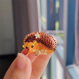 Détail d'une broche hérisson orange faite à la main avec une petite fleur blanche