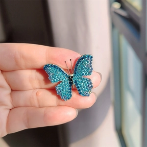 Detail of hand-held butterfly brooch with blue rhinestones and gradient crystal inlay
